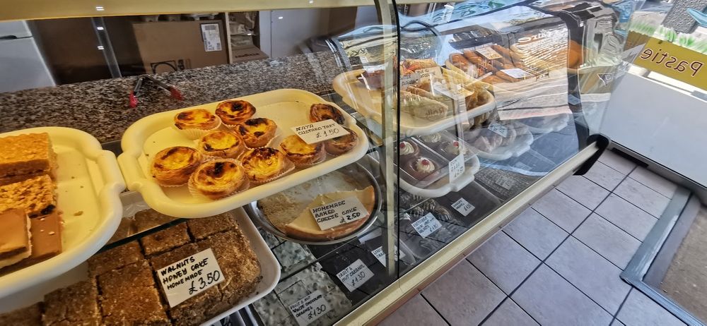 The pastry counter seen from the side, custard tarts, cakes and slices under glass